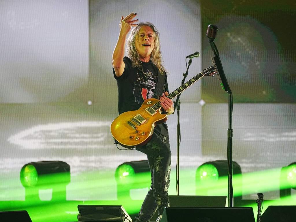 Gitaris Metallica Kirk Hammett saat beraksi di atas panggung dengan gitarnya.